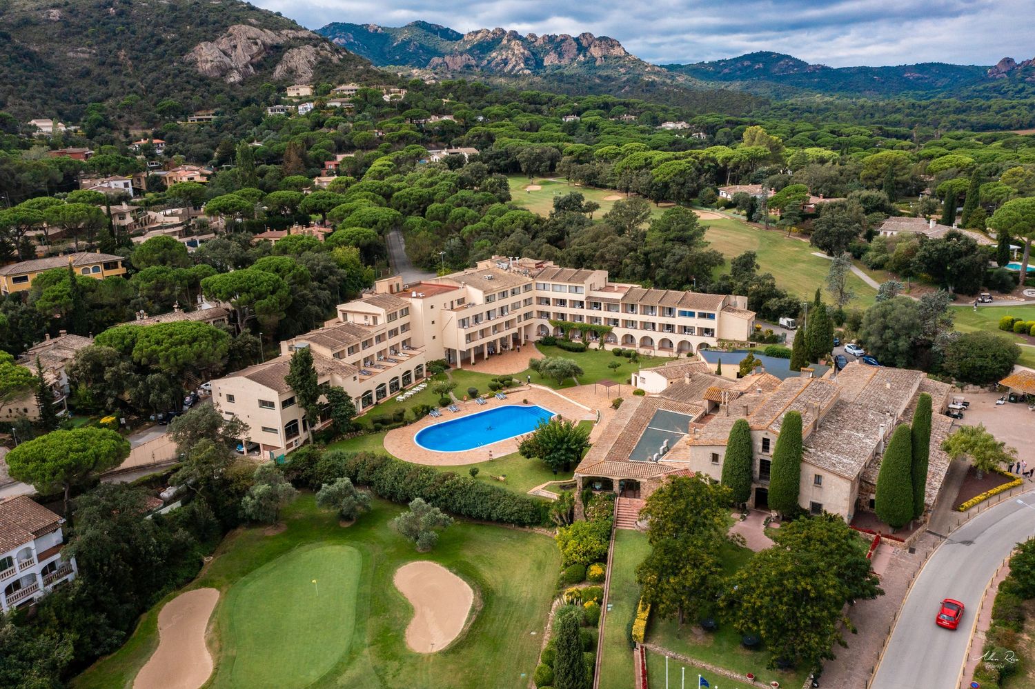 Aerial view of a luxury hotel resort with pool surrounded by golf course and mountains in Spain.