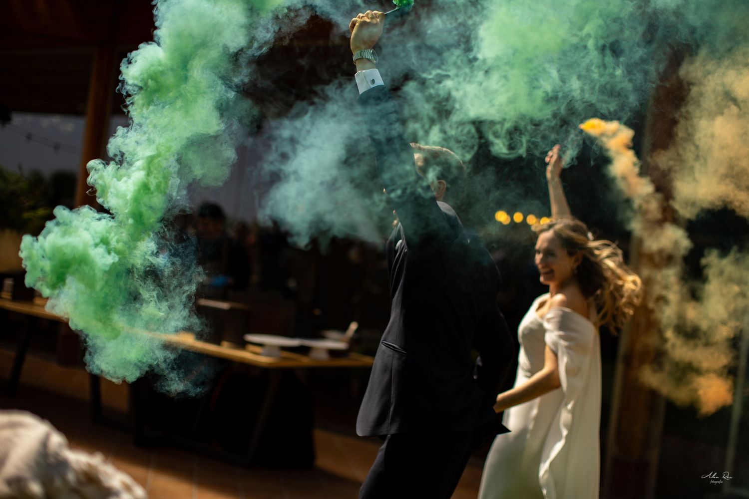 Bride and groom celebrate with colorful green and yellow smoke bombs on the dance floor.