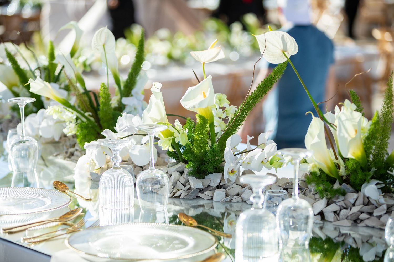 Close-up of wedding table centerpiece featuring white calla lilies, hydrangeas, and ferns.