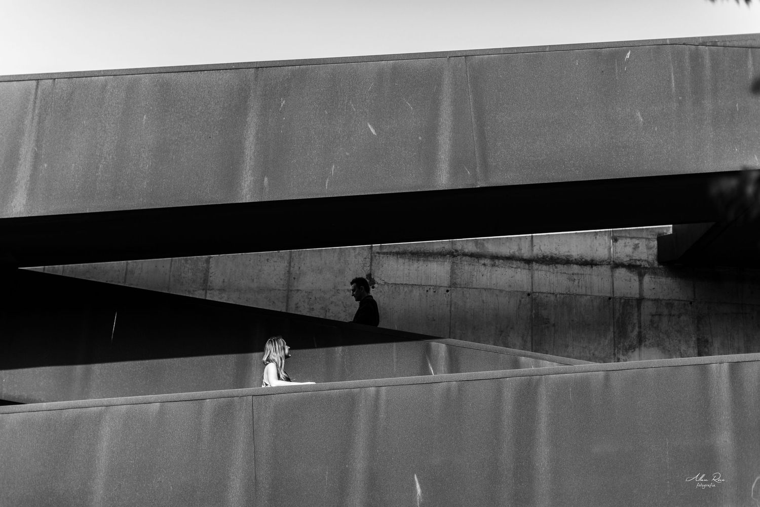 Black and white photo of a child standing between concrete walls with a shadow cast above.