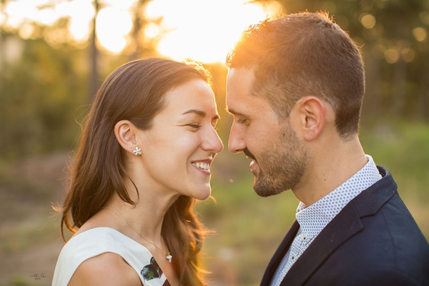 Smiling couple sharing a joyful close moment bathed in warm golden sunlight.