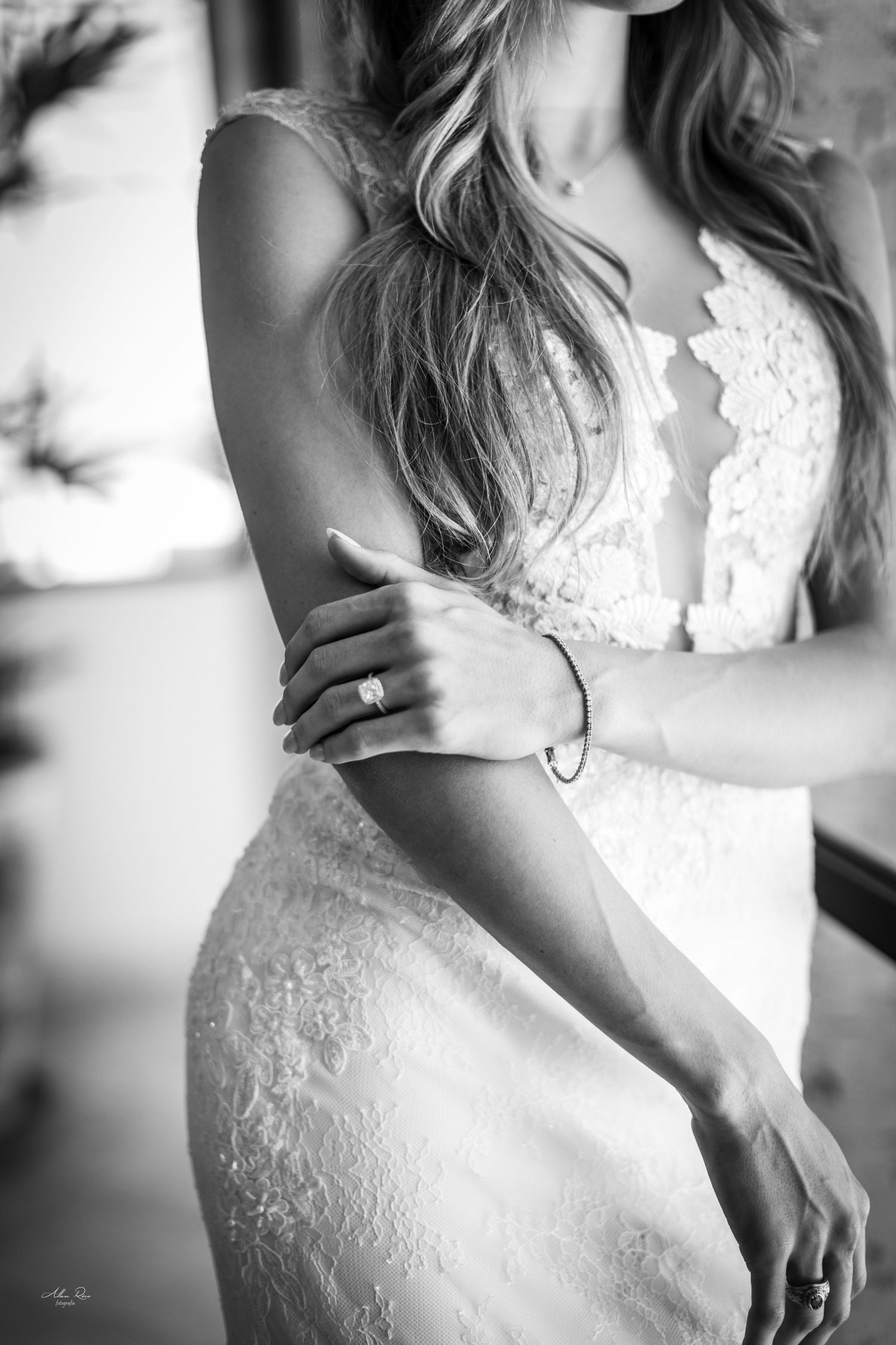 Black and white close-up of bride in lace gown showcasing engagement ring and delicate bracelet.