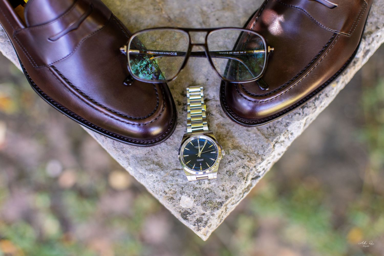 Groom accessories flat lay with brown loafers, aviator glasses, and gold watch.