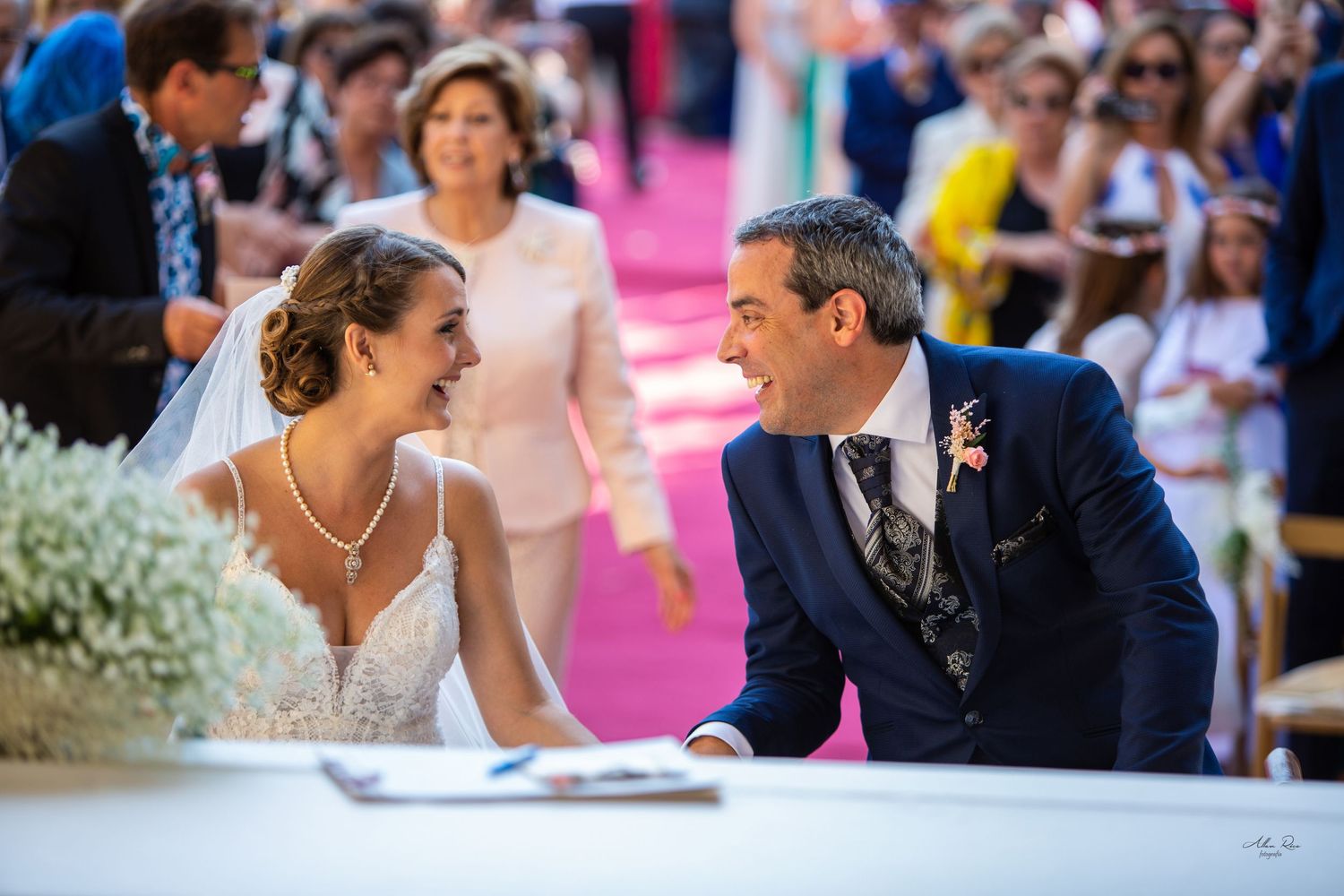 Bride and groom share a joyful moment at the signing table during their outdoor wedding ceremony.