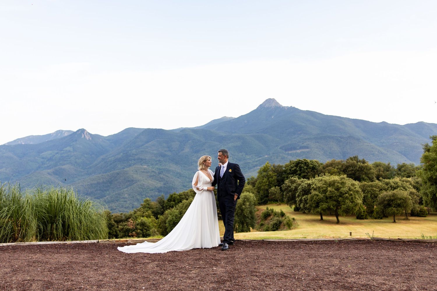 Bride and groom stand together with stunning mountain range landscape behind them.