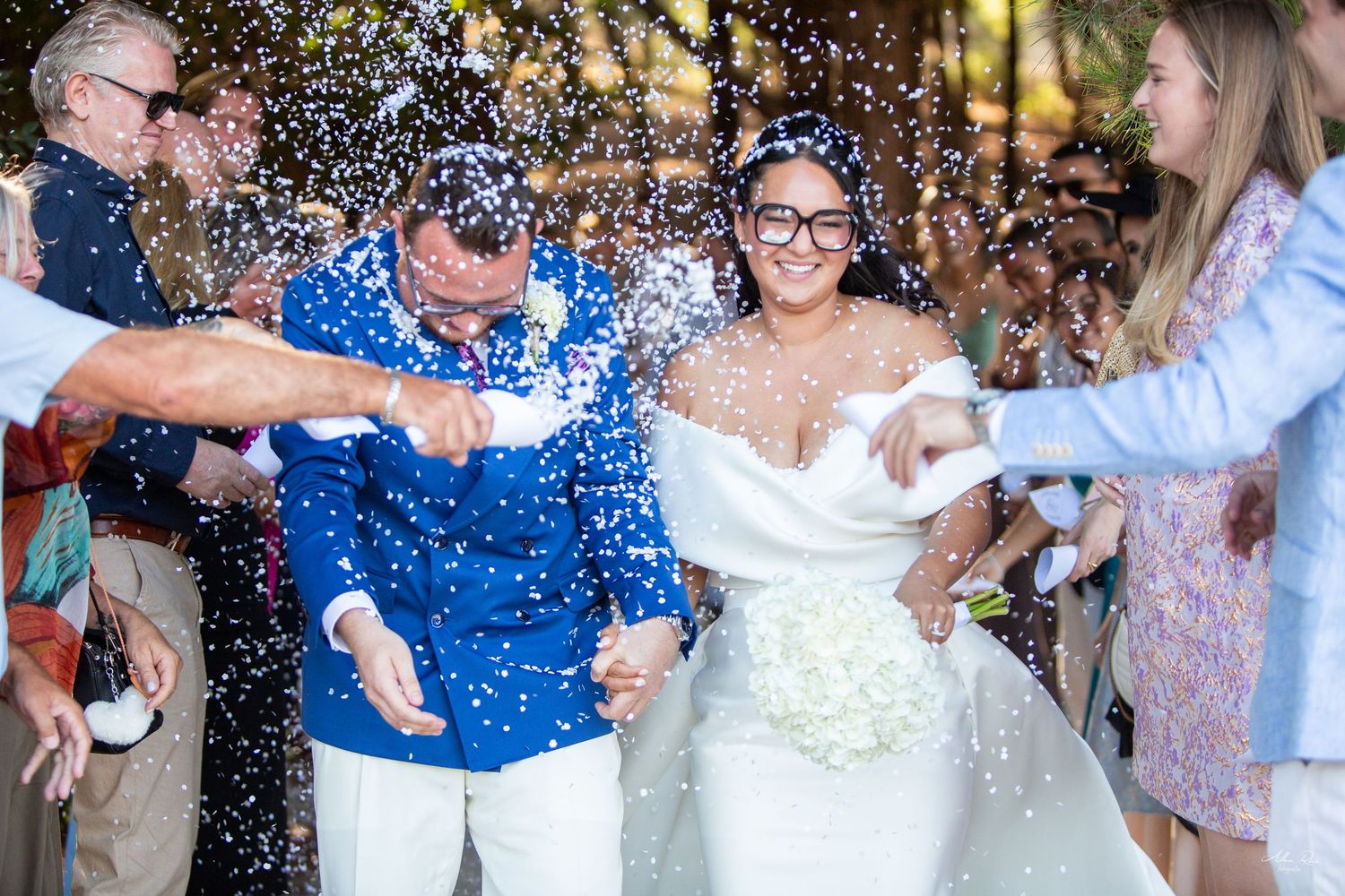 Smiling bride and groom celebrate with confetti toss during joyful outdoor wedding reception.
