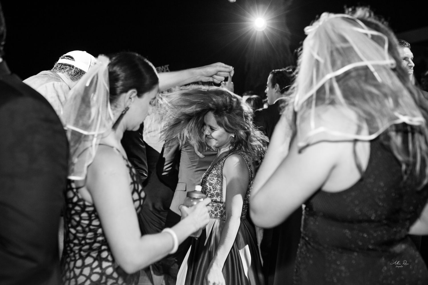Bride and guests dancing energetically at a lively black and white wedding reception party.