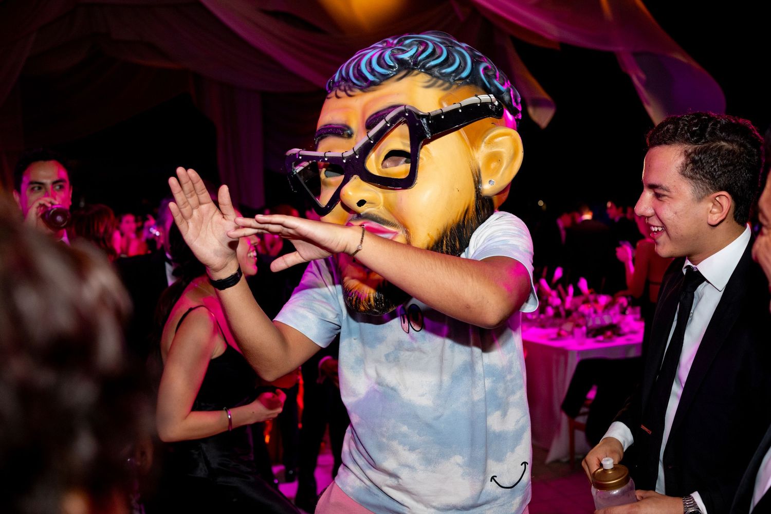 Performer wearing oversized cartoon face mask entertaining guests at a colorful wedding reception.