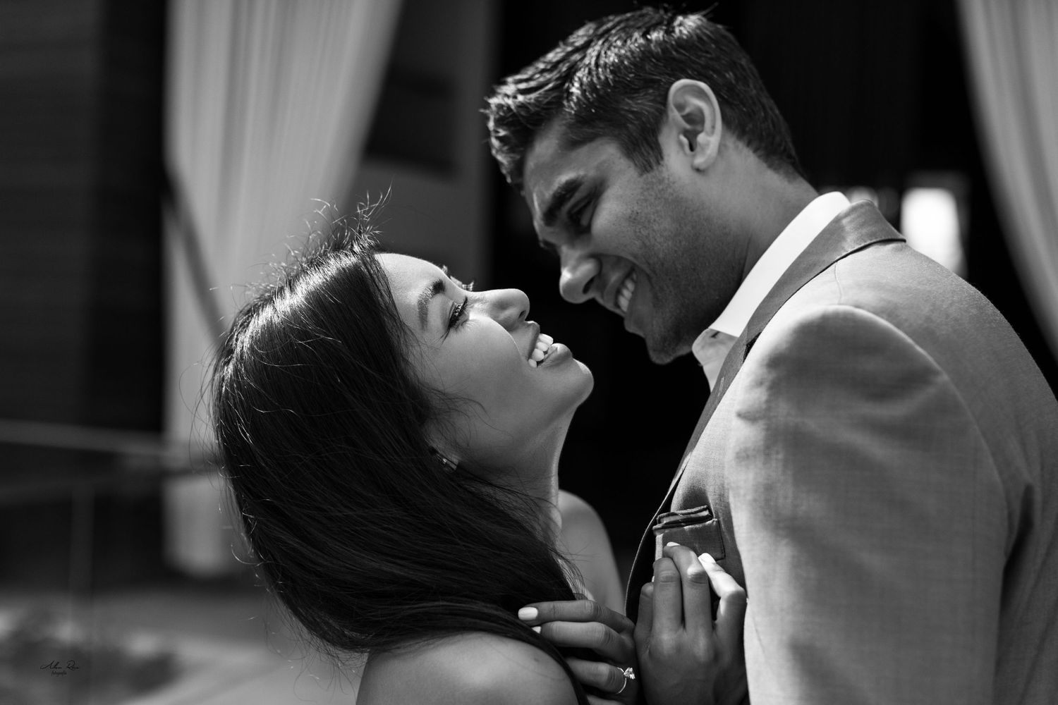 Black and white photo of a joyful couple sharing an intimate moment at an engagement session.