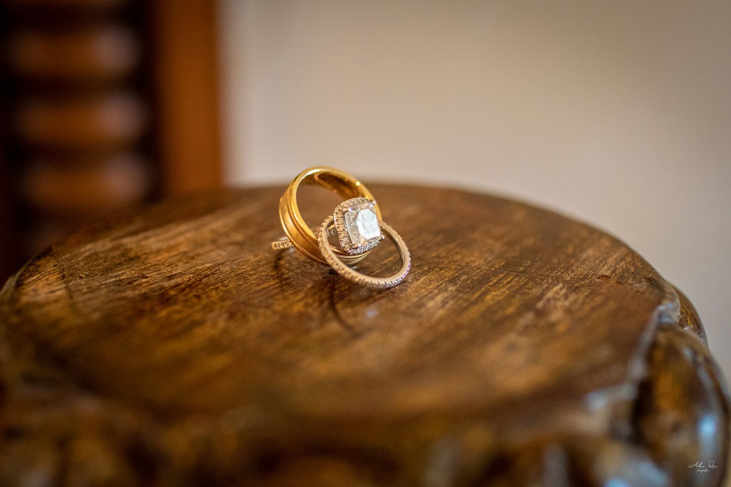 Gold wedding engagement ring with diamond center stone displayed on rustic wooden surface.