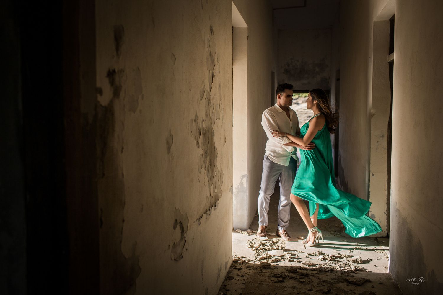 Romantic couple embracing in a flowing green dress inside an abandoned building corridor in Los Cabos.