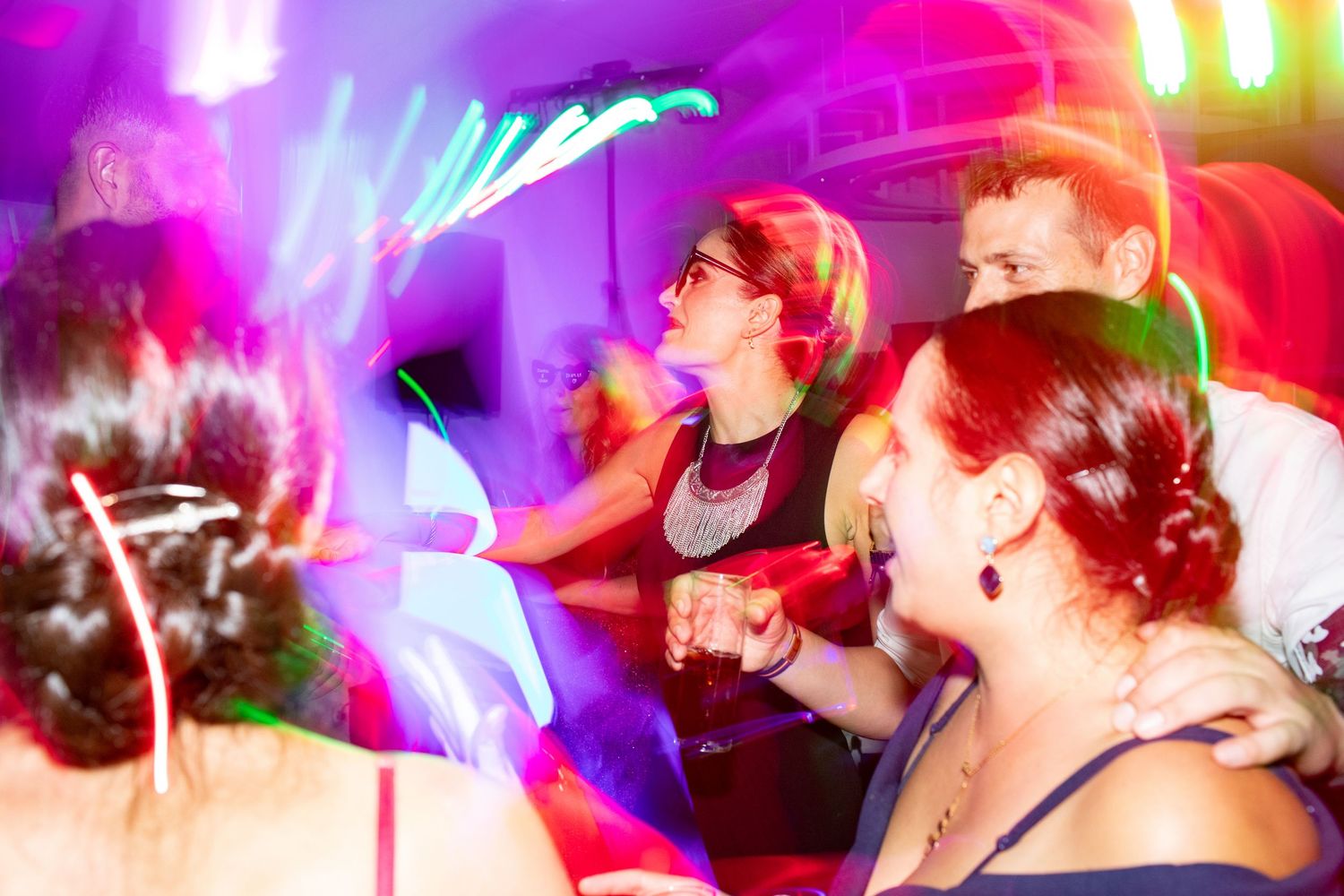 Wedding guests dancing under colorful neon lights at lively wedding reception party.