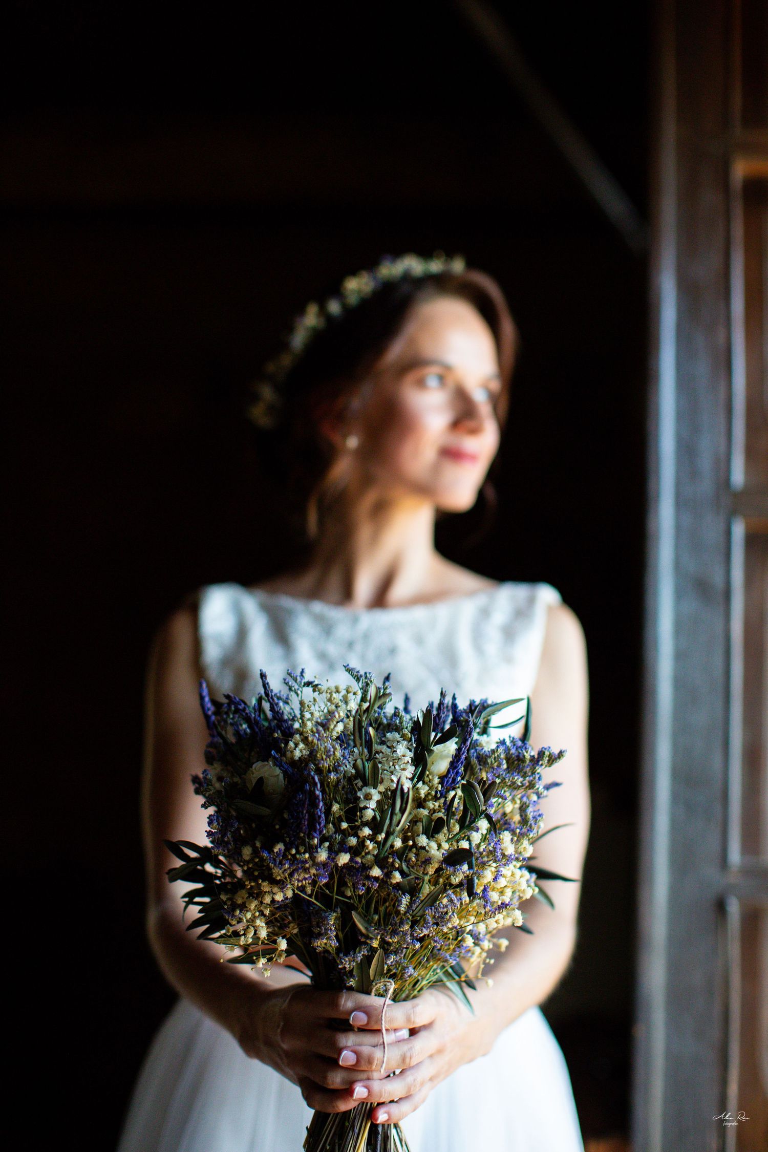 Close-up of bride holding blue and white wildflower bouquet in white sleeveless wedding dress.