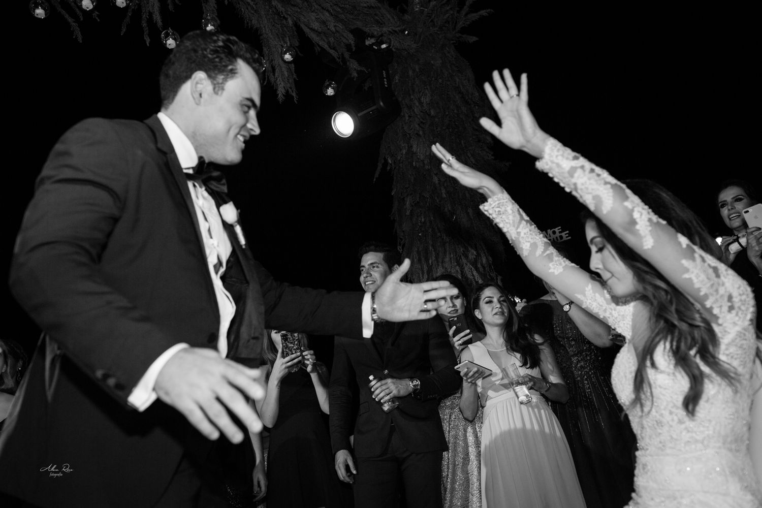 Bride and groom dancing joyfully with guests at wedding reception.