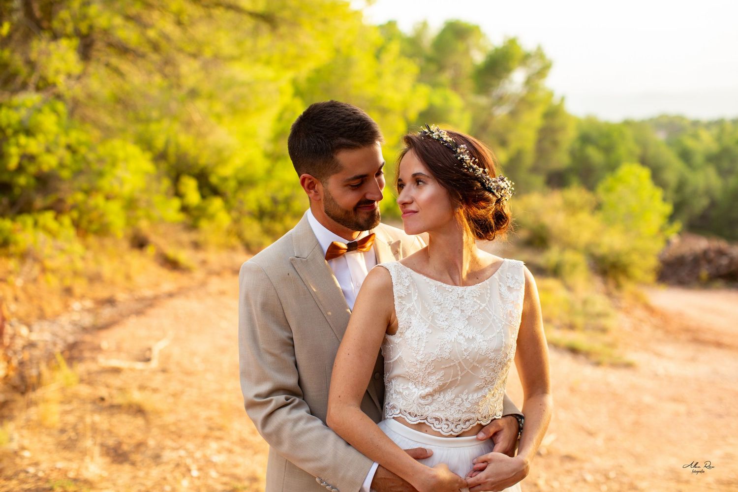 Bride and groom sharing an intimate gaze on a rustic dirt path surrounded by autumn trees.