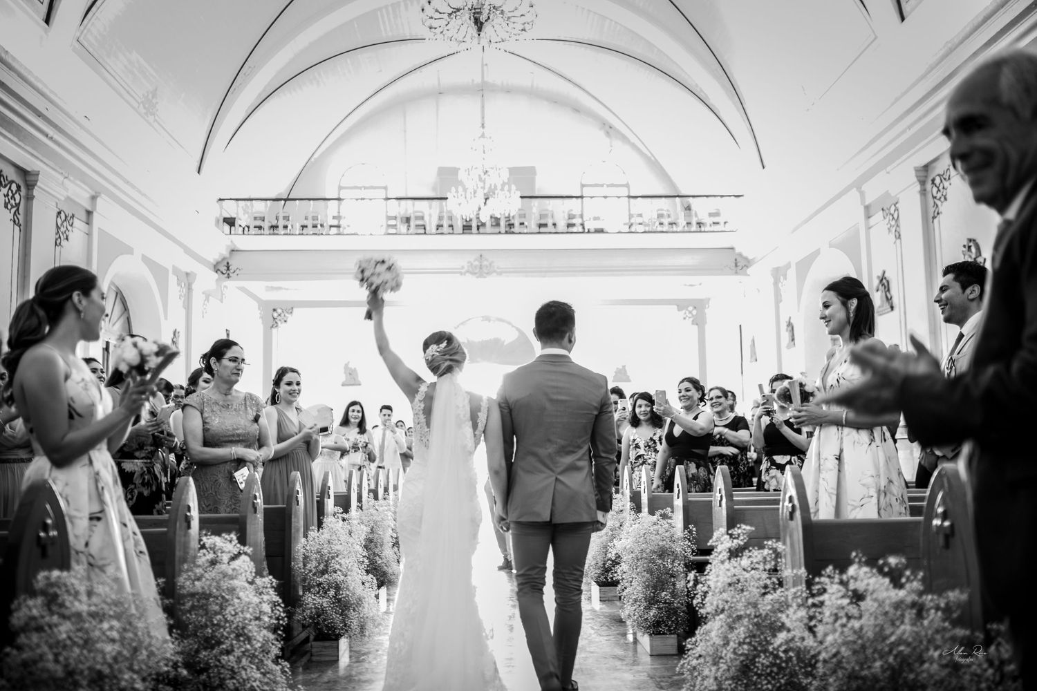 Bride and groom walk down church aisle as guests celebrate their wedding ceremony.