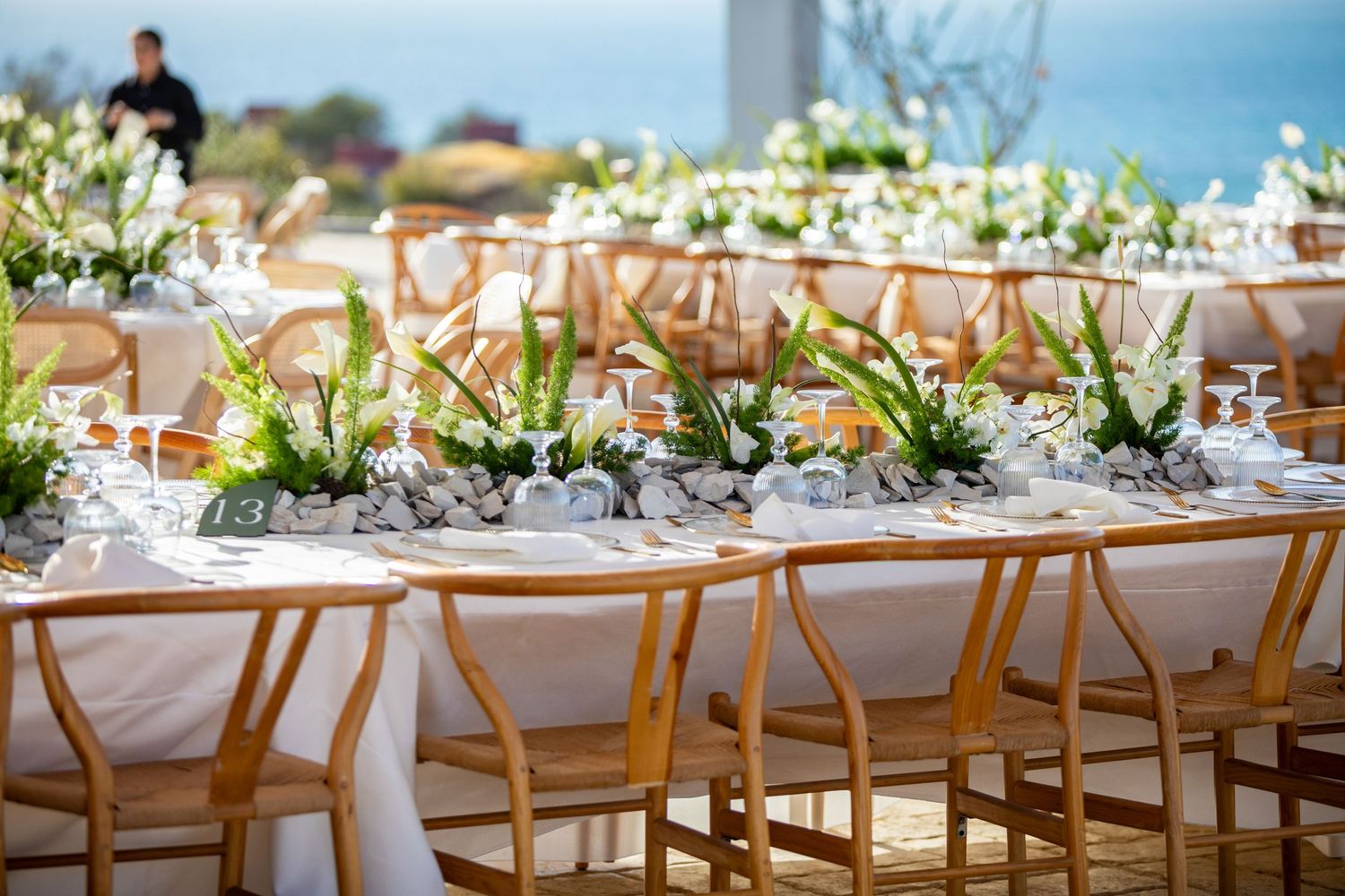 Beautifully set wedding banquet tables with white orchid centerpieces and wooden wishbone chairs.