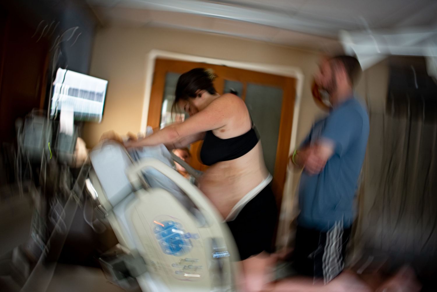 Blurred artistic photo capturing intense home birth labor scene with support partner present.