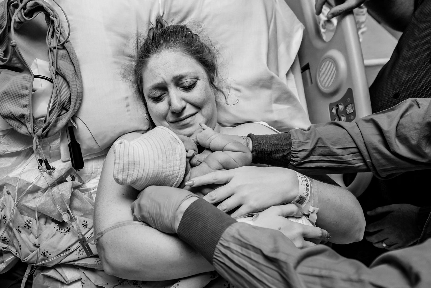 Emotional black and white photo of mother clutching newborn after hospital delivery.