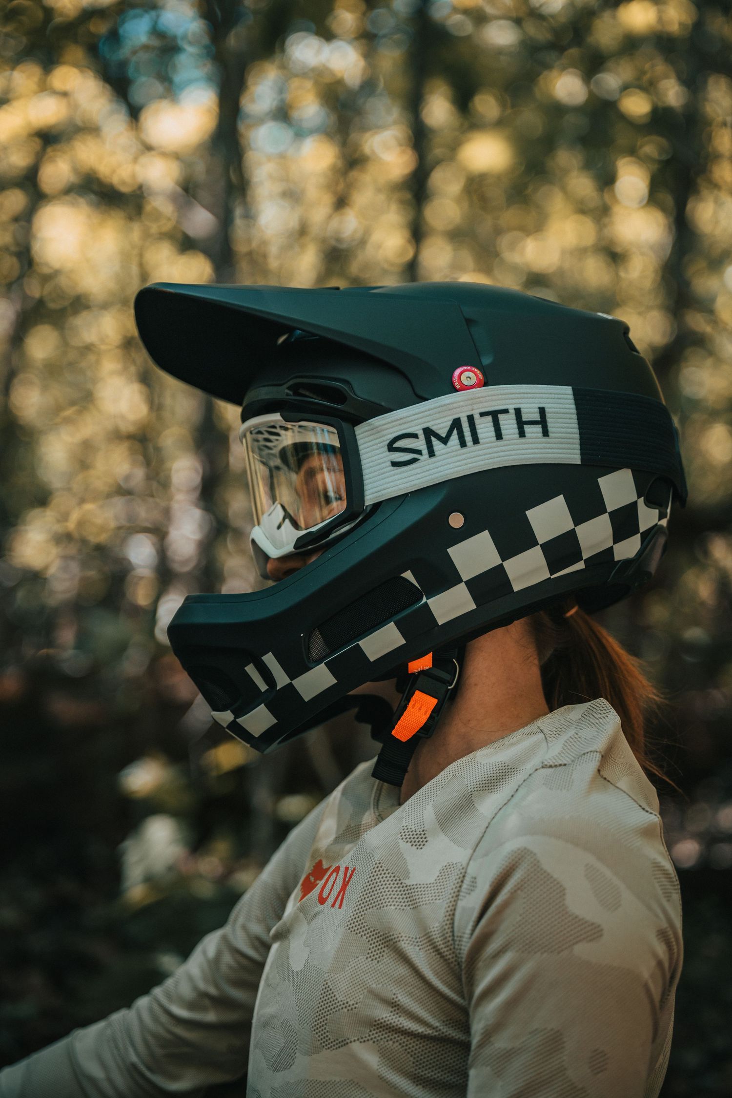 Close-up profile of a rider wearing a black and white checkered full-face MTB helmet.