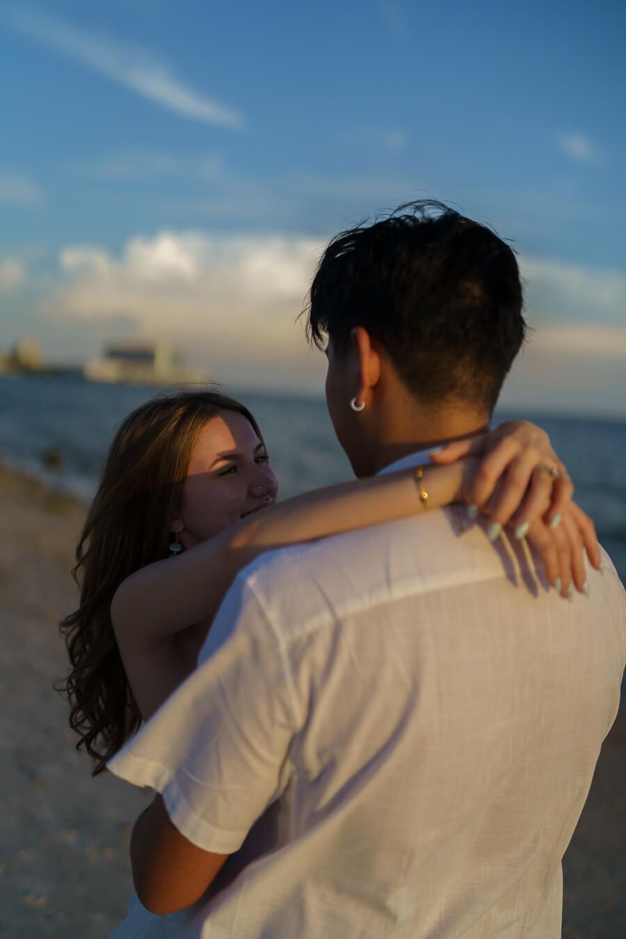 photo of couples at a beach putting her arms around him