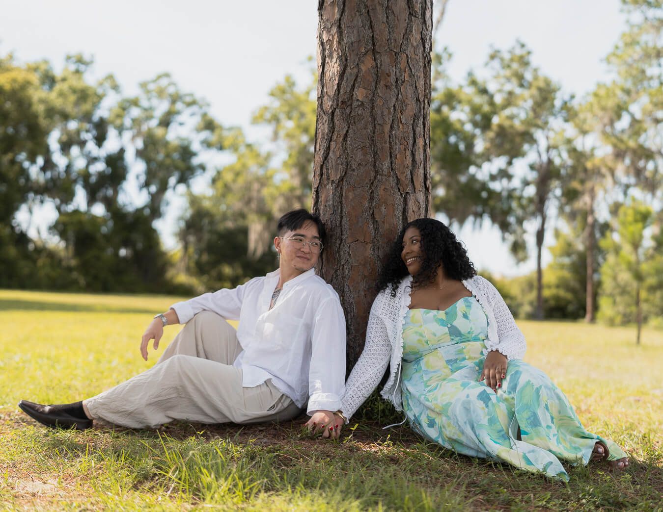 Couple sitting by a pine tree during an outdoor portrait session in Tampa, Florida