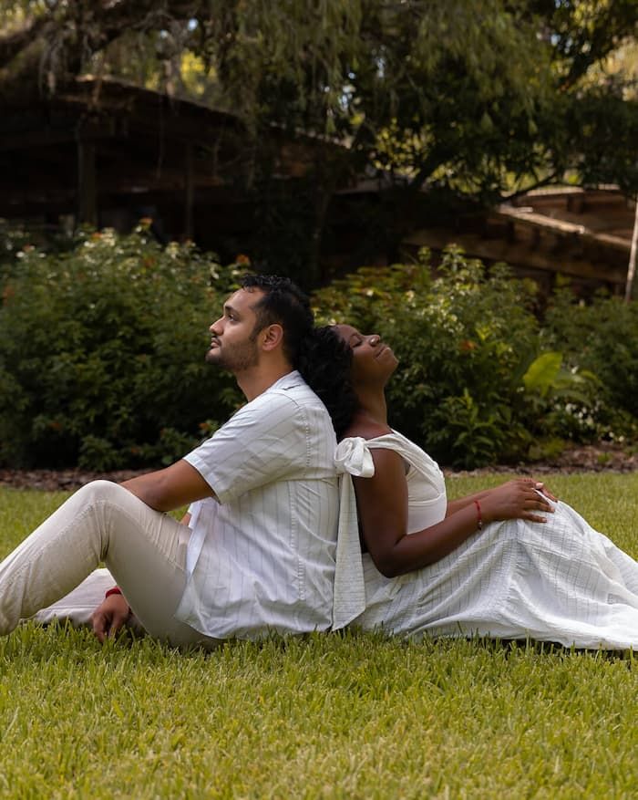 Romantic couples and engagement session of a couple sitting back to back on grass in Tampa, Florida, captured by James Jang Photography