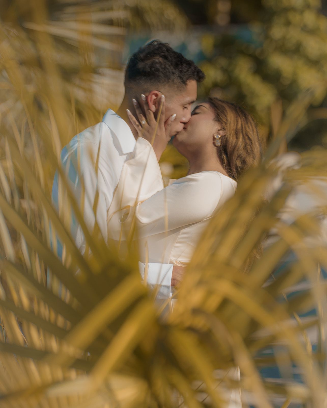 Couple kissing framed behind golden palm fronds