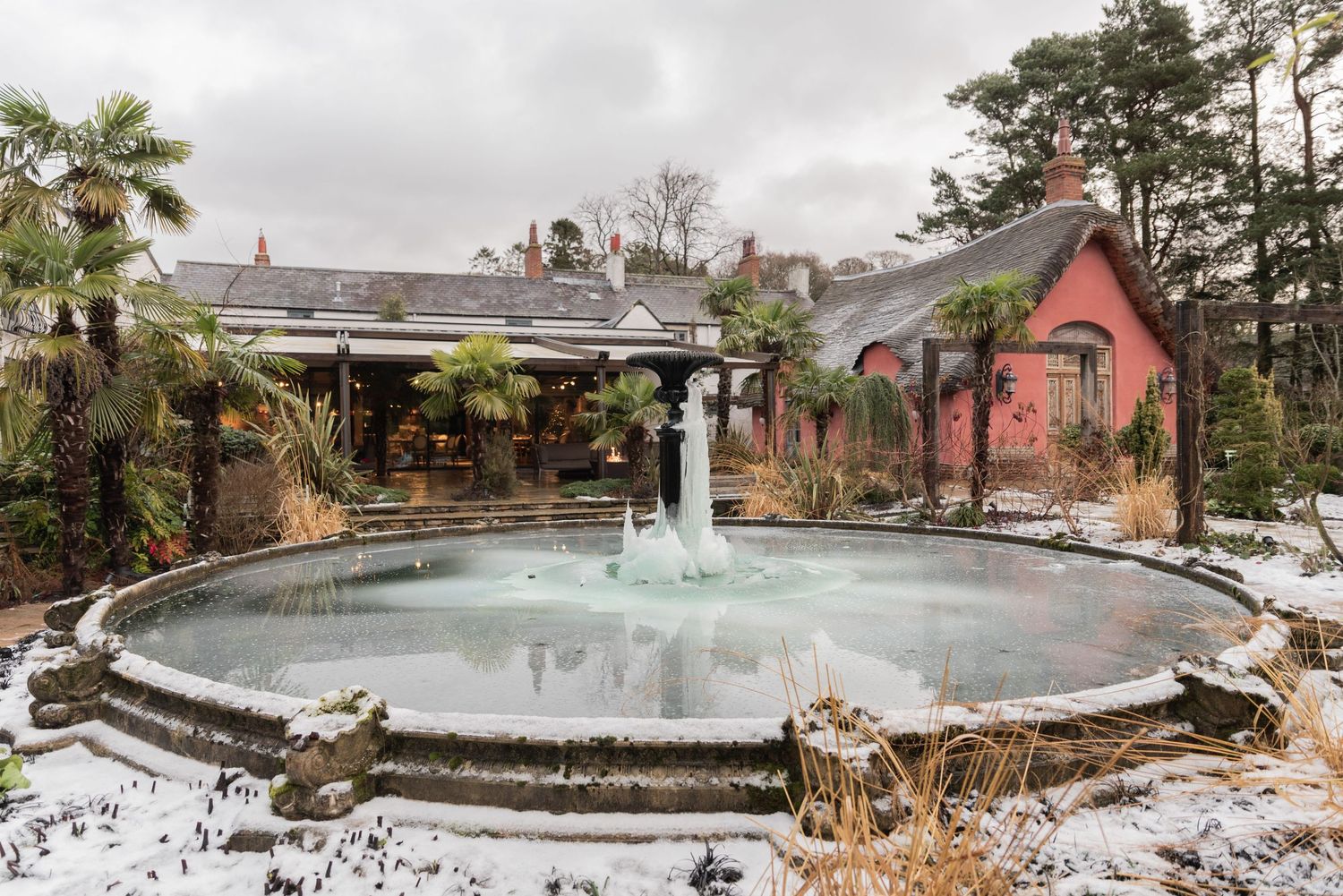 Snow lying on the ground around a frozen water fountain at Le Petit Chateau. Jagged shards of ice hang down from the fountain centrepiece.
