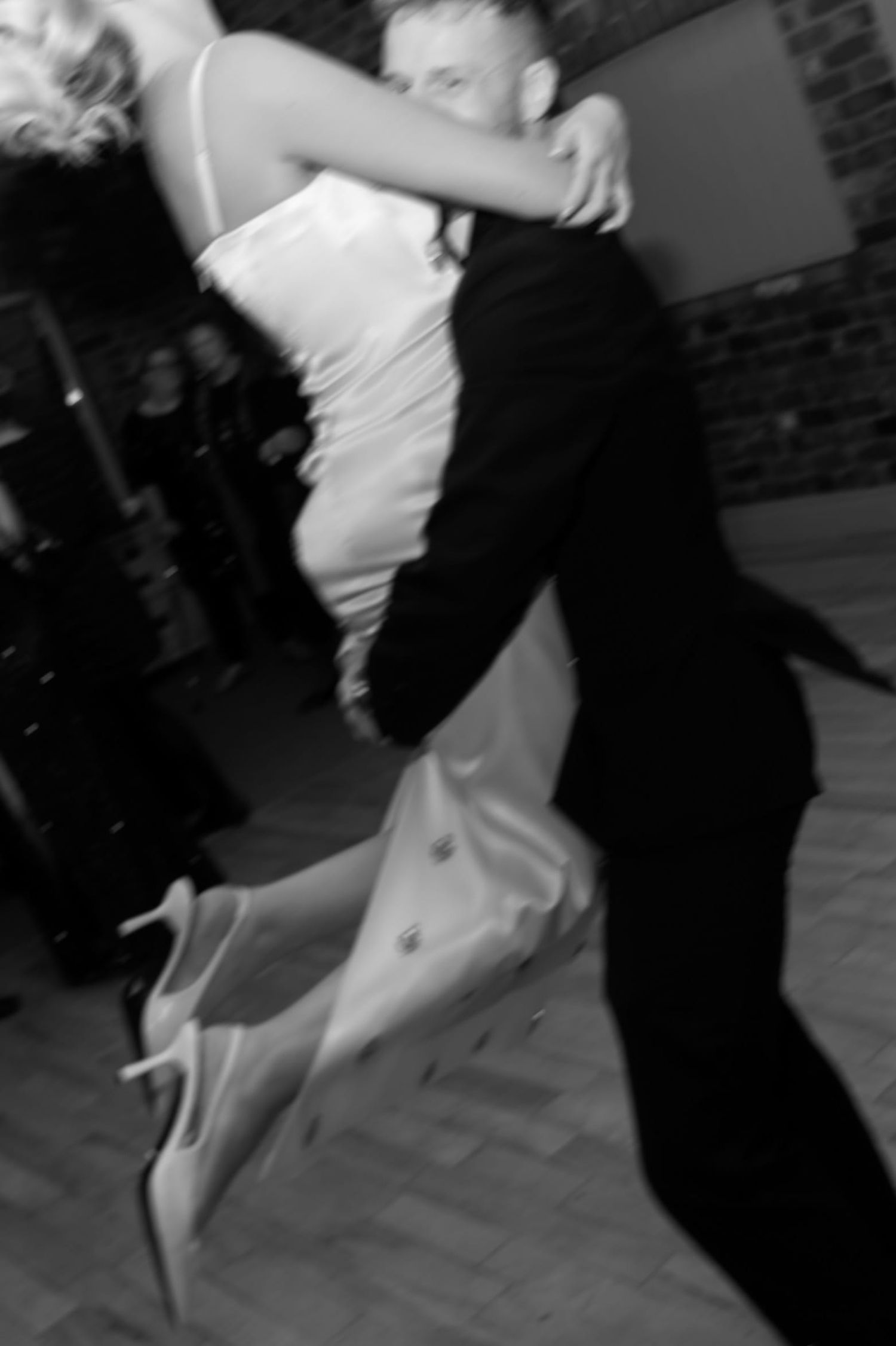 Groom holding his new wife high in the air spinning her around on a dance floor. He is wearing a tuxedo and she has a long fitted silk gown.