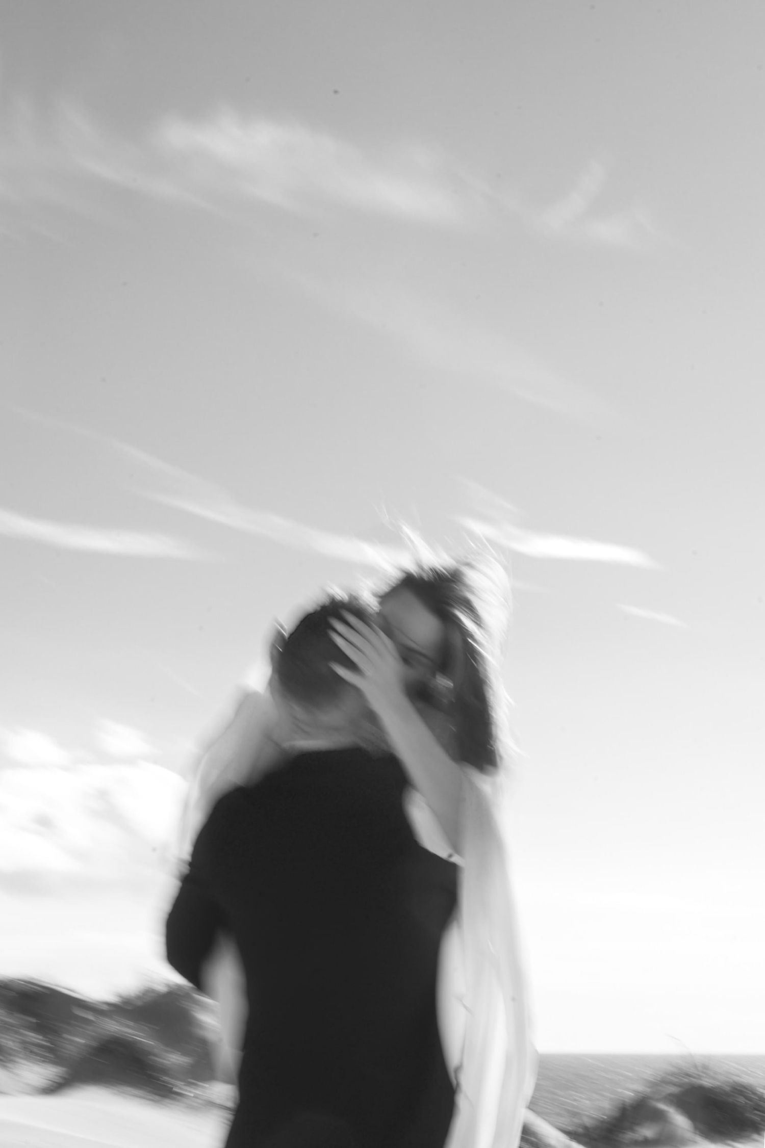 Blurry image of a man holding up a woman, she has her hands around his head and they are kissing passionately.