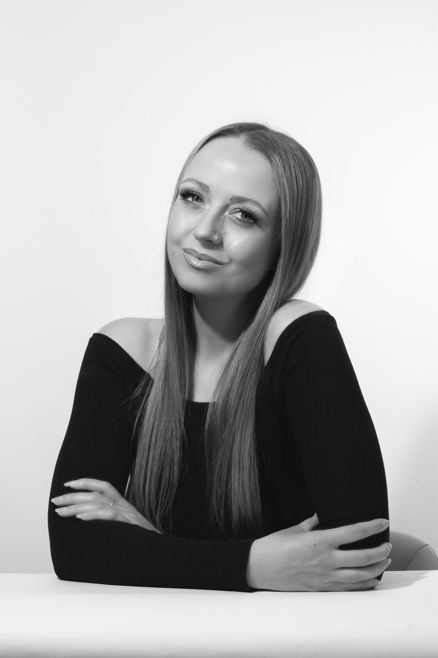 Headshot of a woman with long straight hair smiling to camera with her arms folded.