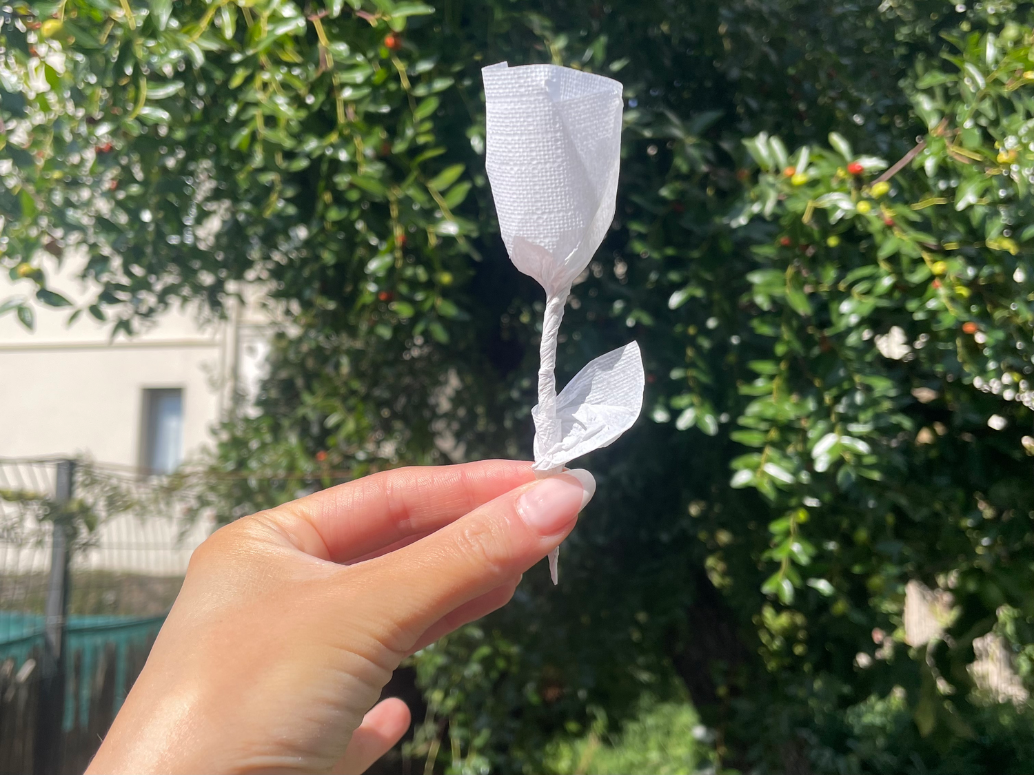 Napkin paper rose held up in a woman's hand.