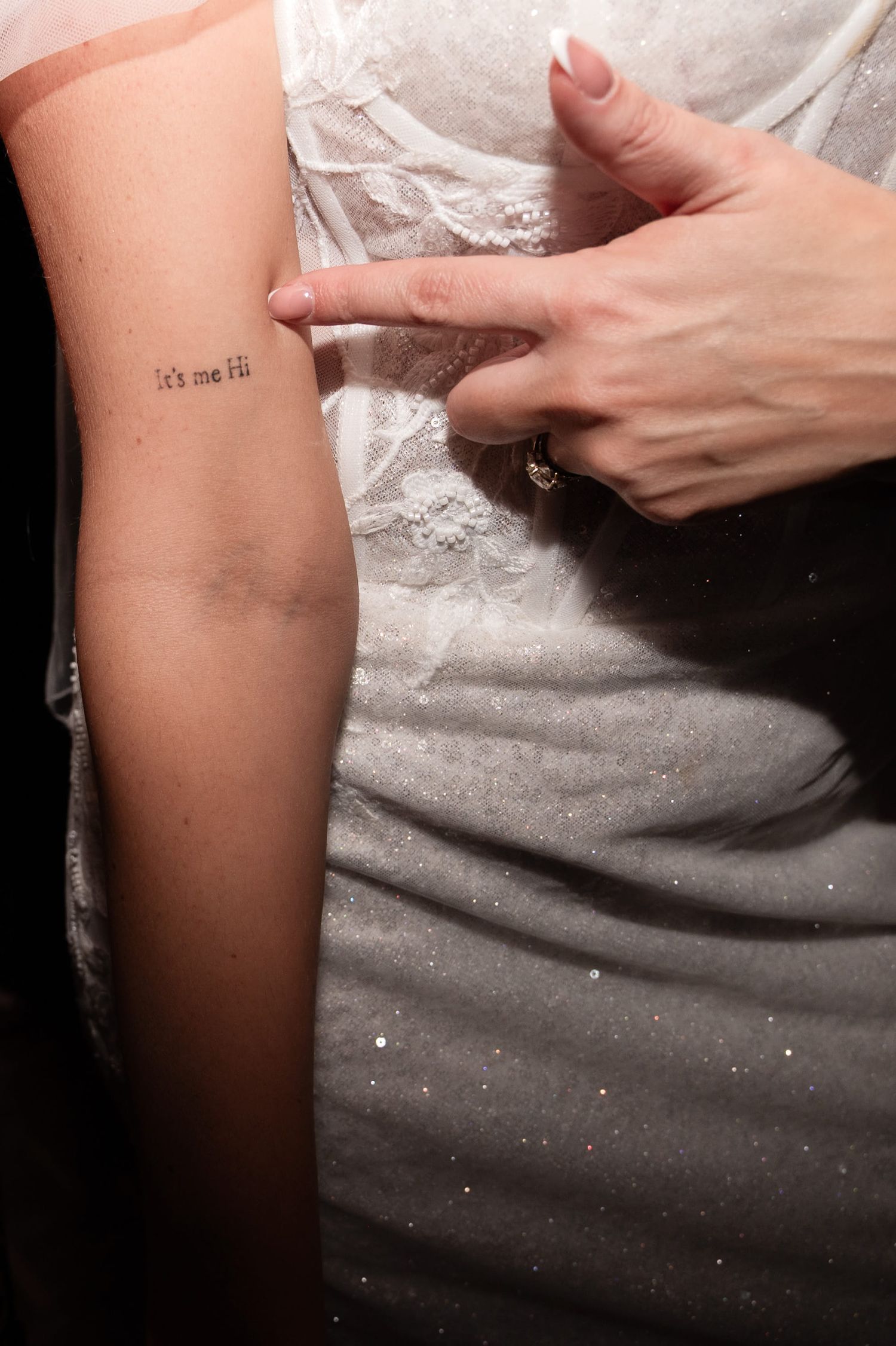 A bride points to her Taylor Swift tattoo on her wedding day. It reads 