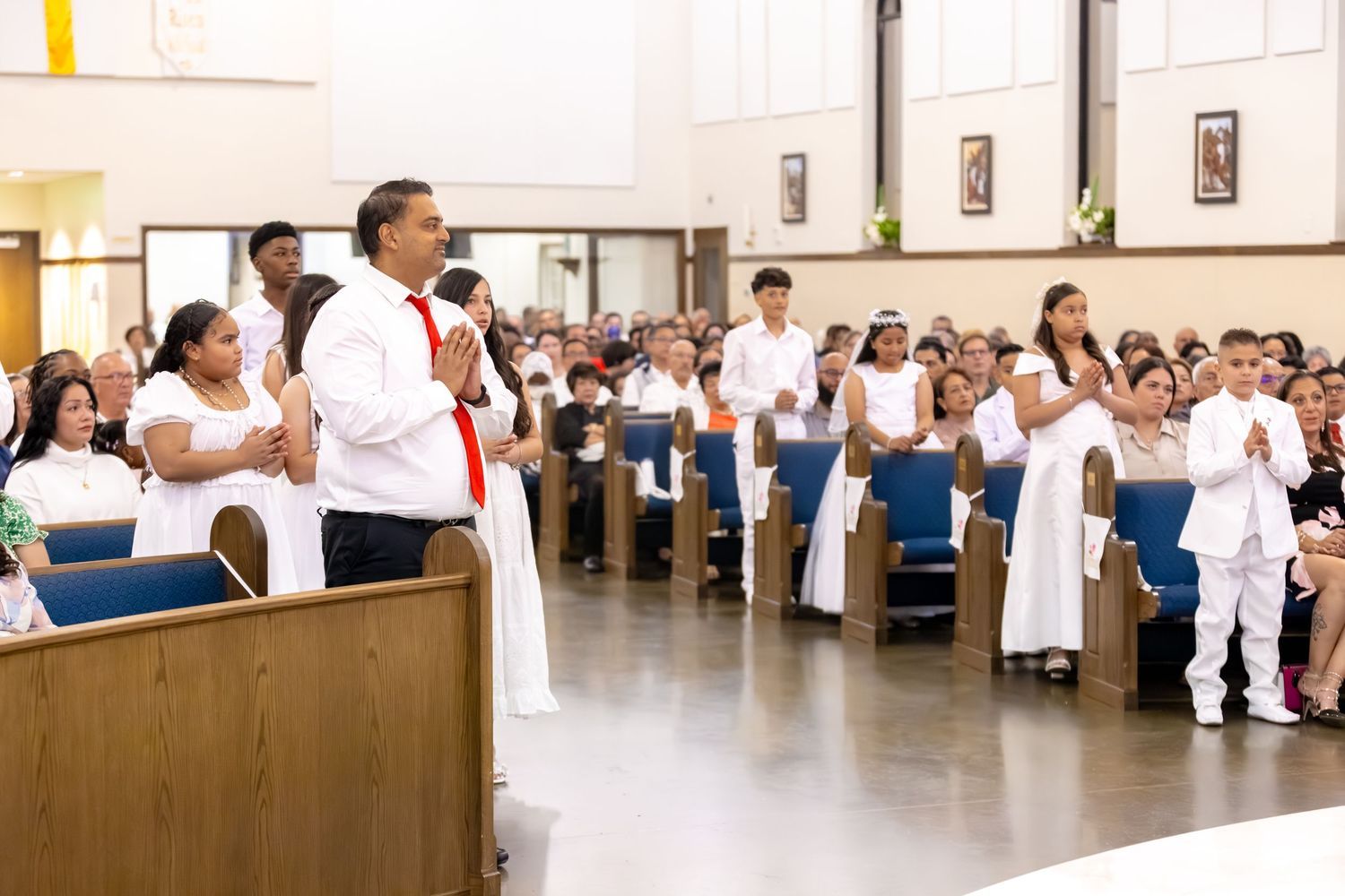 A man in a white shirt and red tie speaks into a microphone at a podium during a church service.