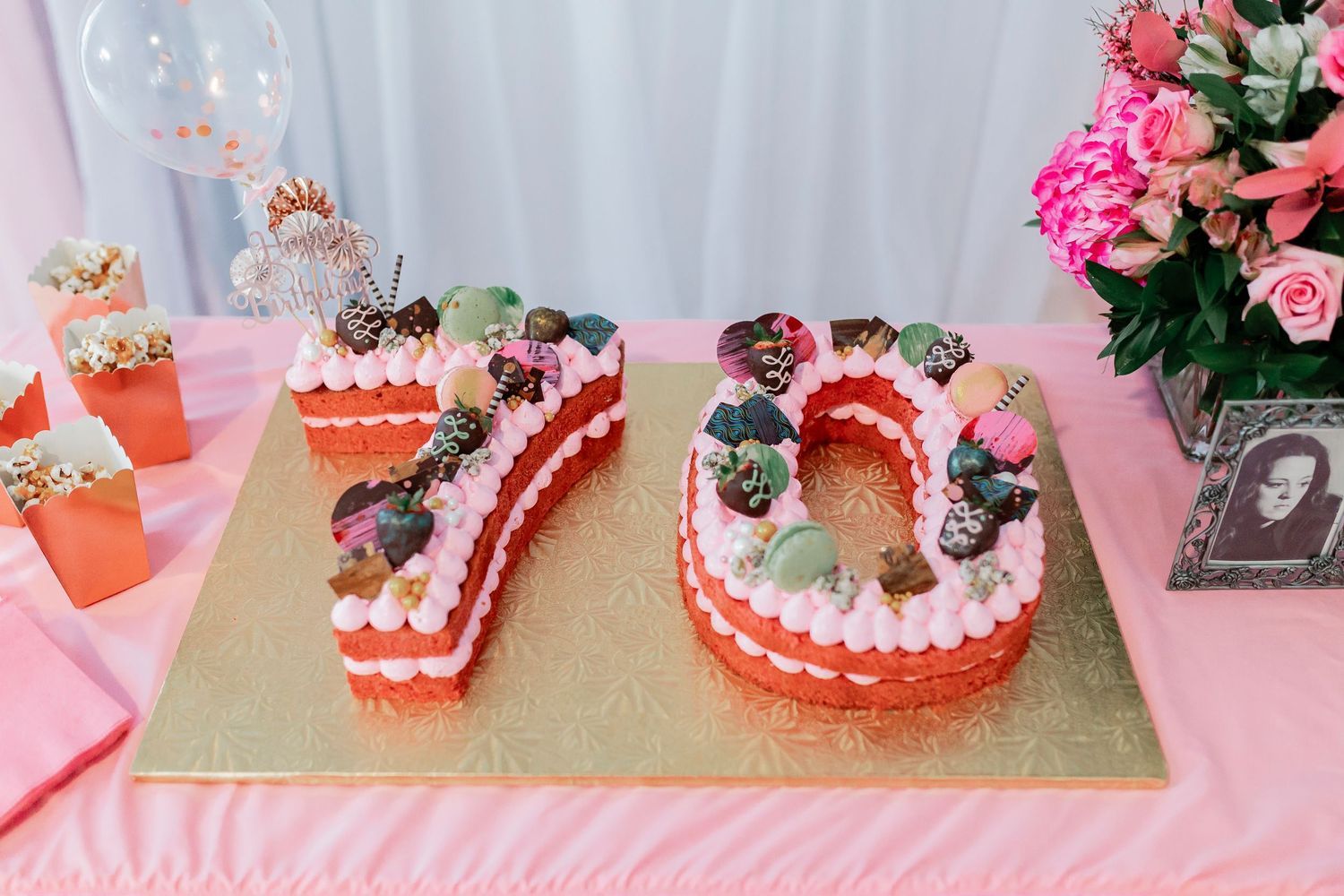 Number 70 shaped birthday cake decorated with fresh berries and cream on a pink party table.