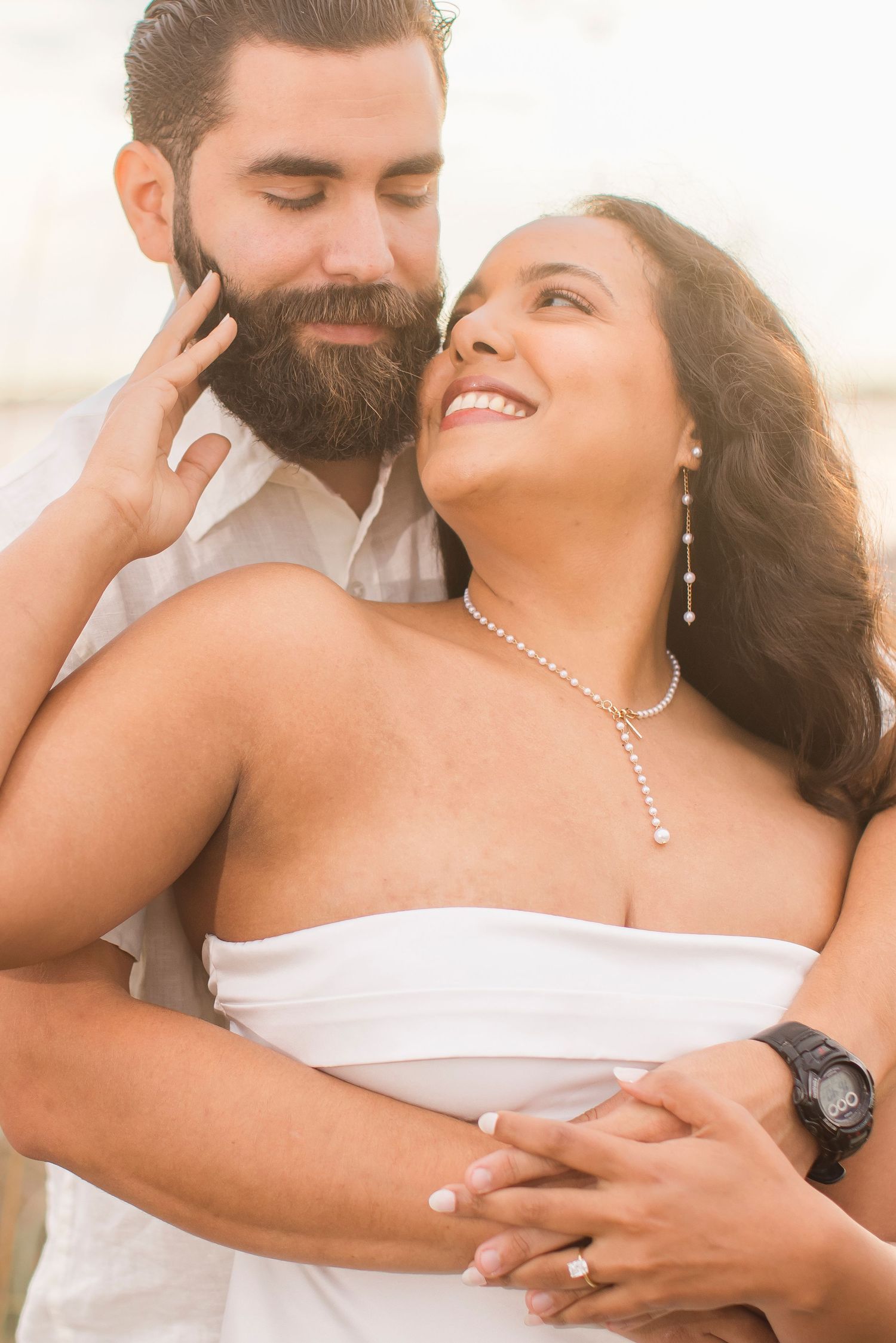 Smiling couple embracing closely at golden hour on the beach.
