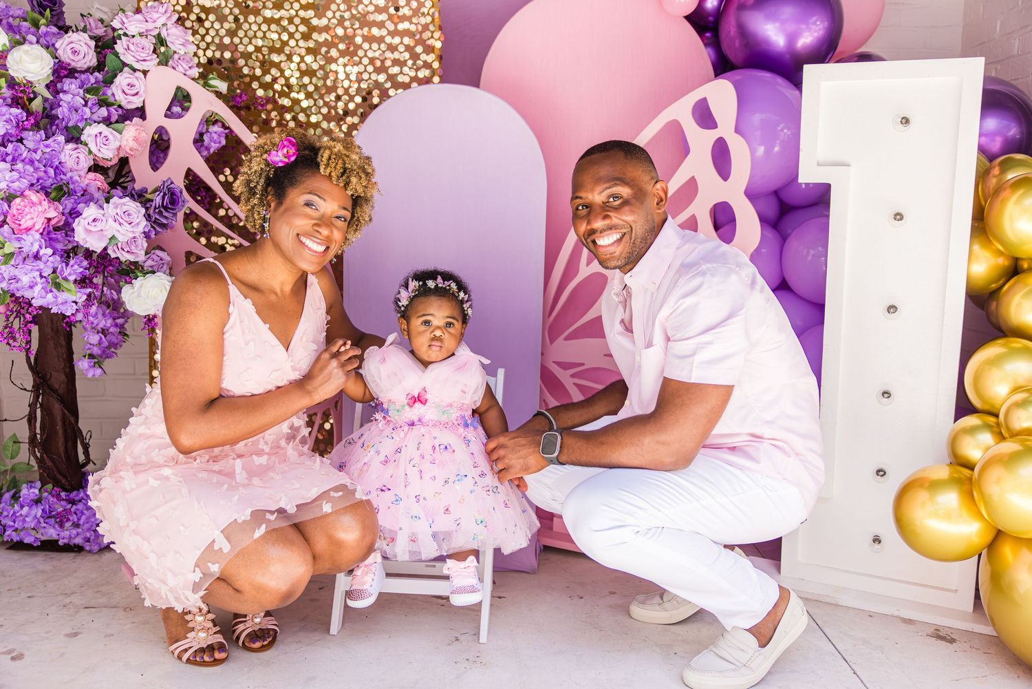 Family photo at a purple butterfly-themed first birthday party with balloons.