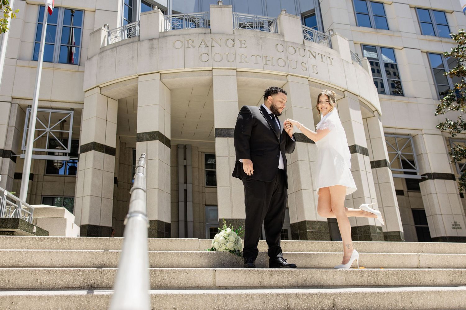Bride and groom celebrate wedding on steps of Orange County courthouse.
