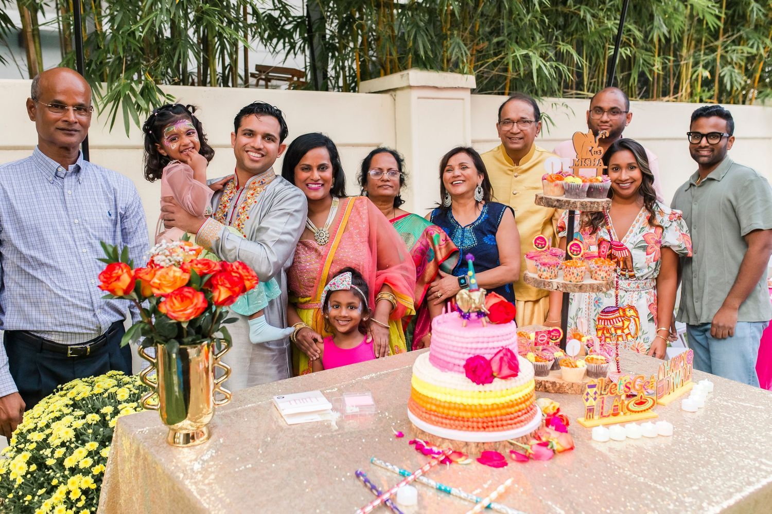 Indian family celebrating birthday with colorful ombre cake and festive decorations.