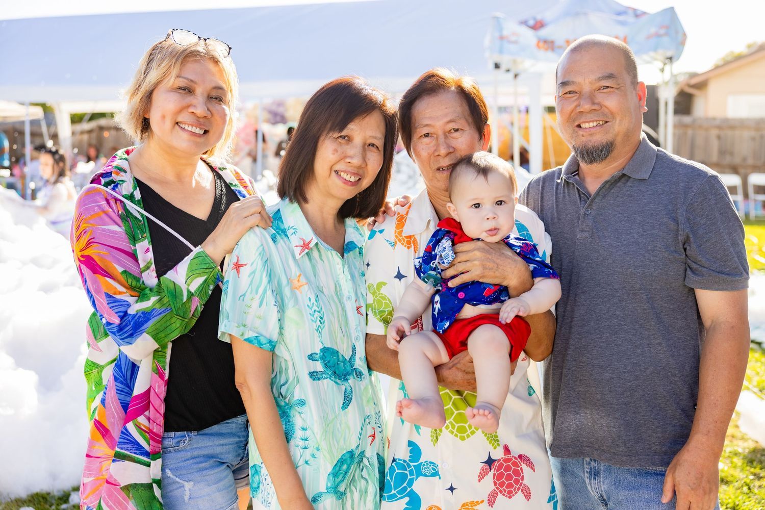 Happy multi-generational Asian family smiling together outdoors at festive foam party event.