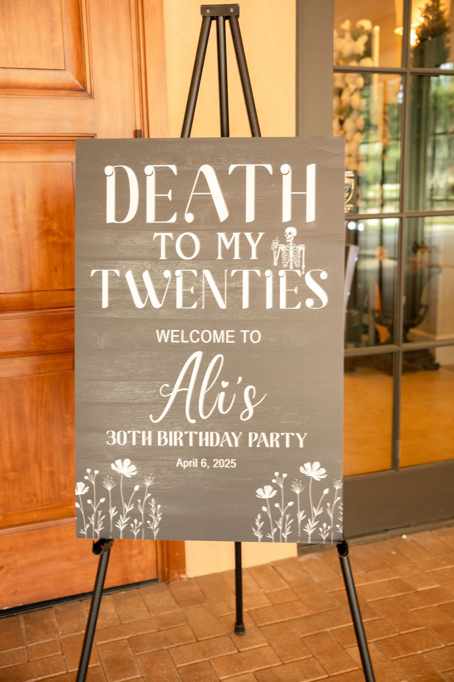 Dark chalkboard welcome sign on easel reads Death to My Twenties for Alis 30th birthday party April 6 2025.