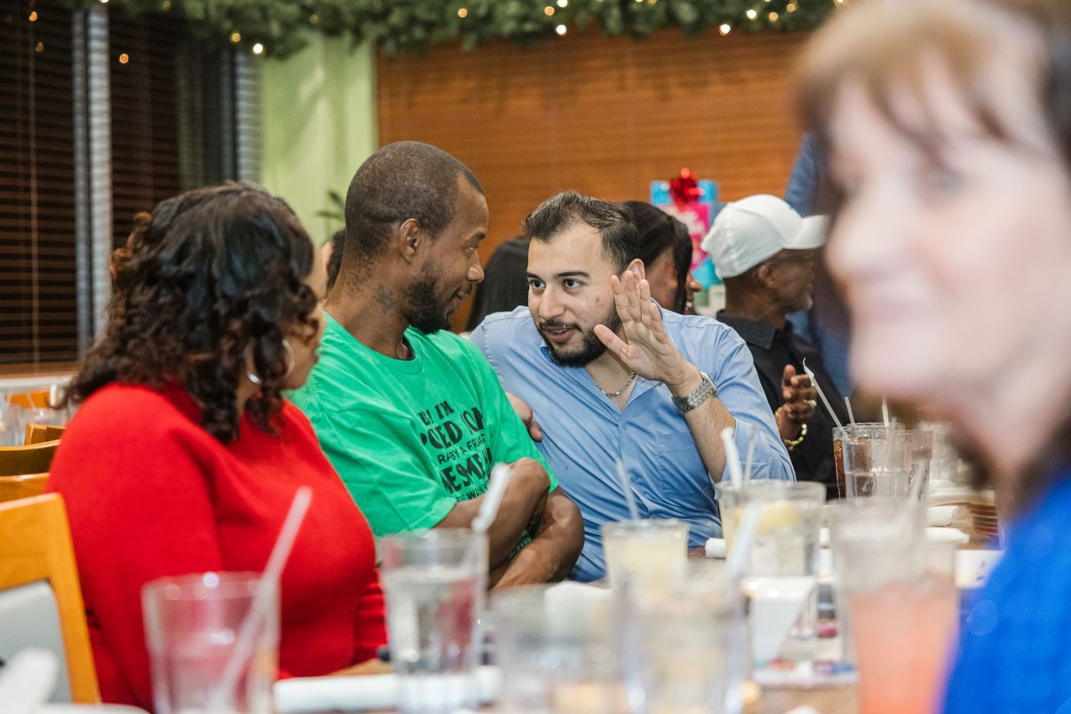 Diverse group of people engaged in lively conversation at holiday dinner gathering.