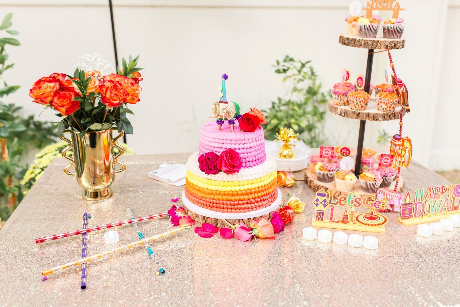 Colorful ombre ruffle birthday cake with flowers on a glittery sequin table.