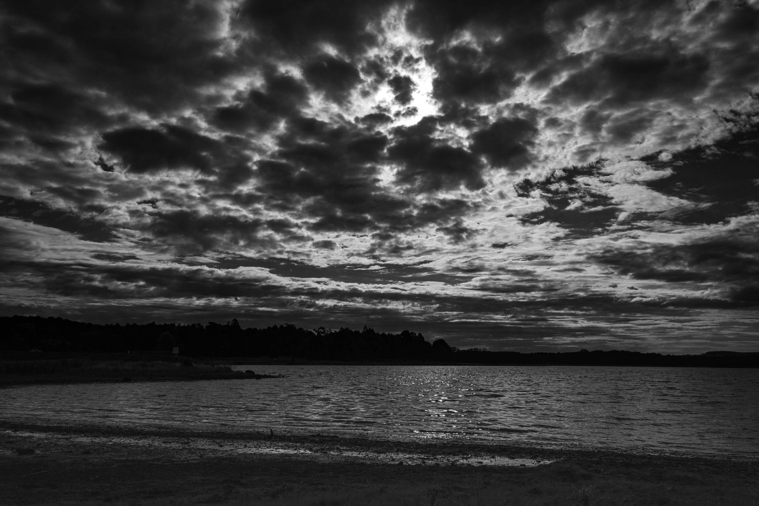 Monochrome image of still water under textured clouds in Victoria