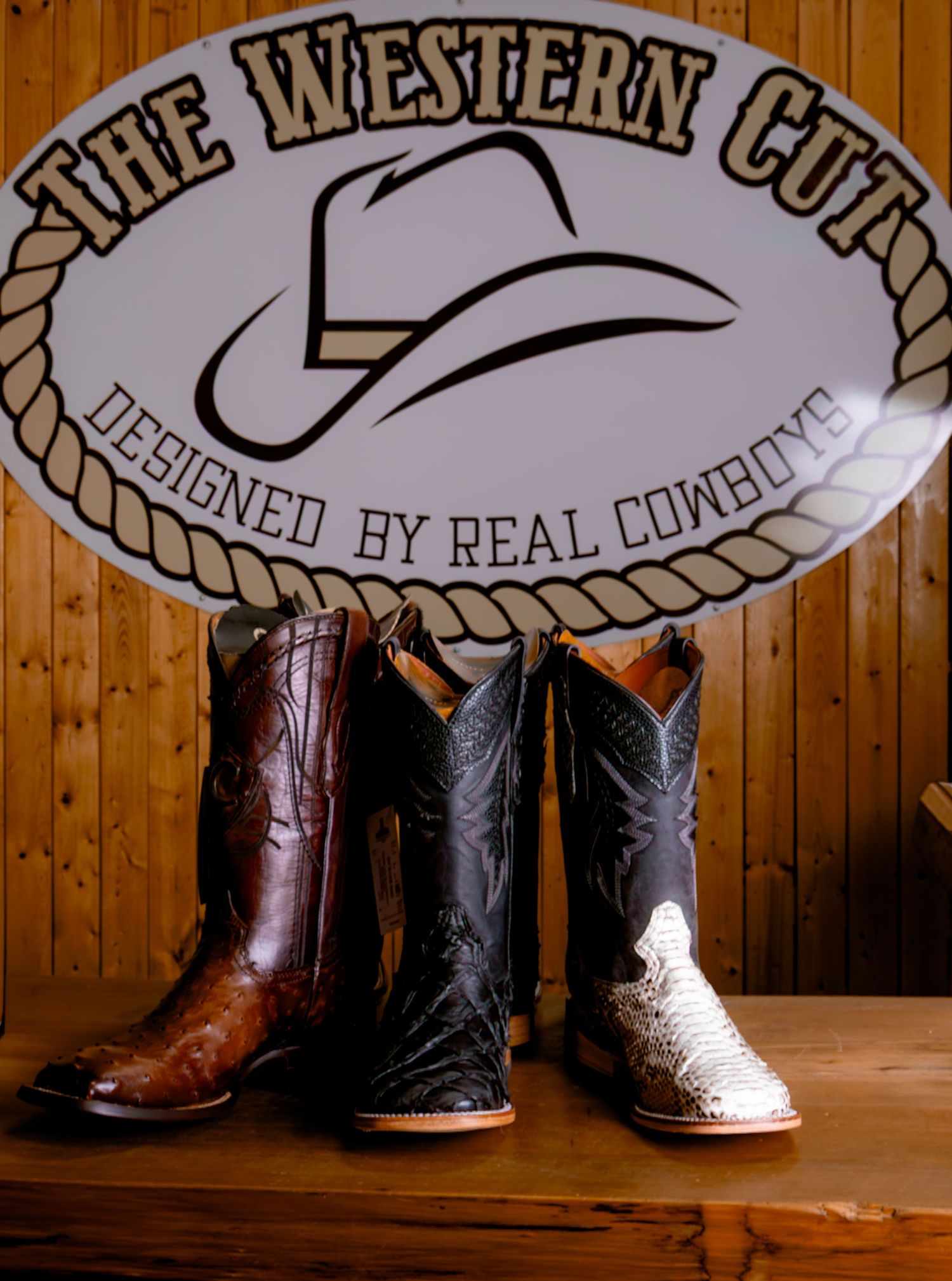 Three pairs of exotic cowboy boots displayed under The Western Cut Designed by Real Cowboys sign.