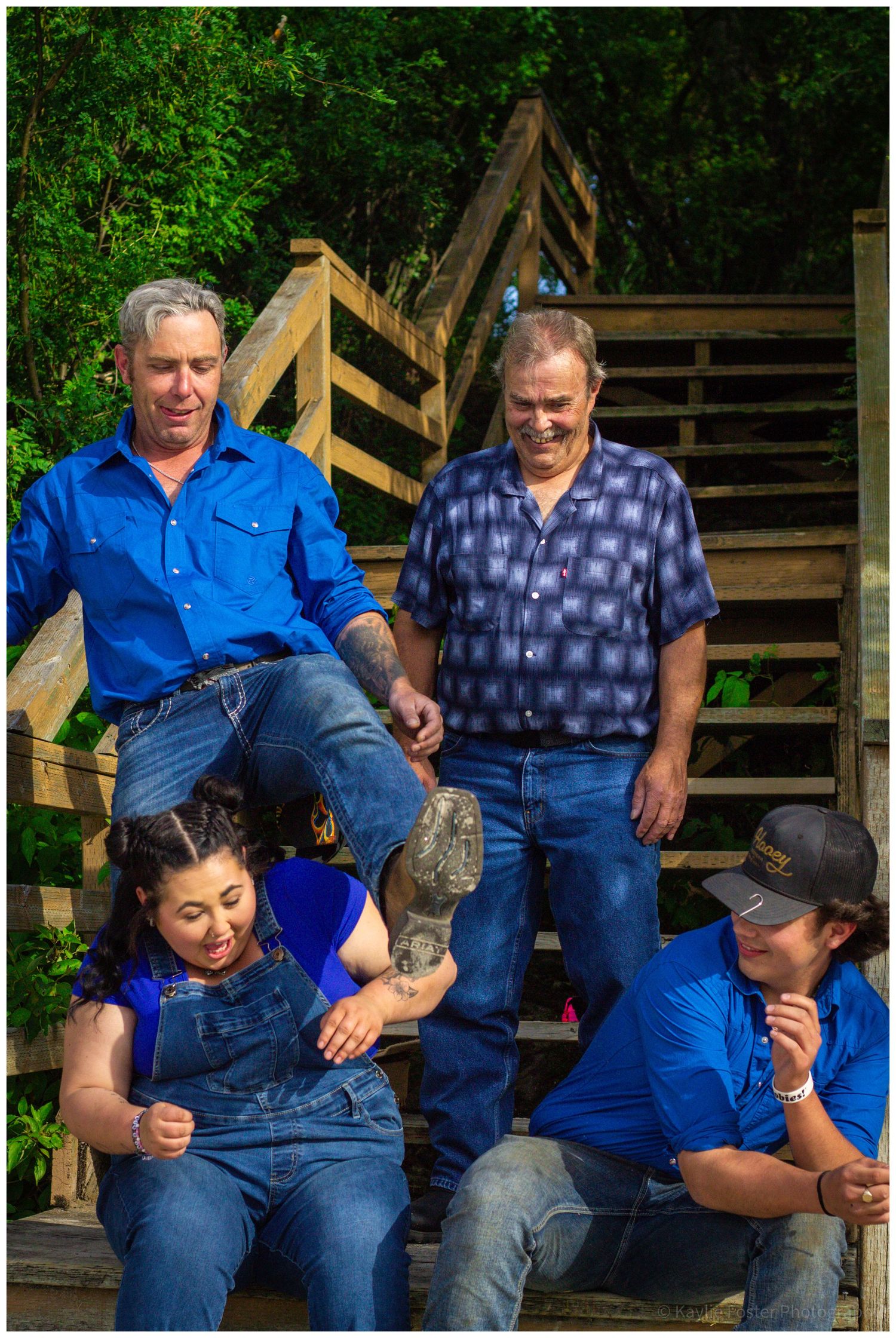 Family group photo on wooden steps with two men and two women in blue outfits.