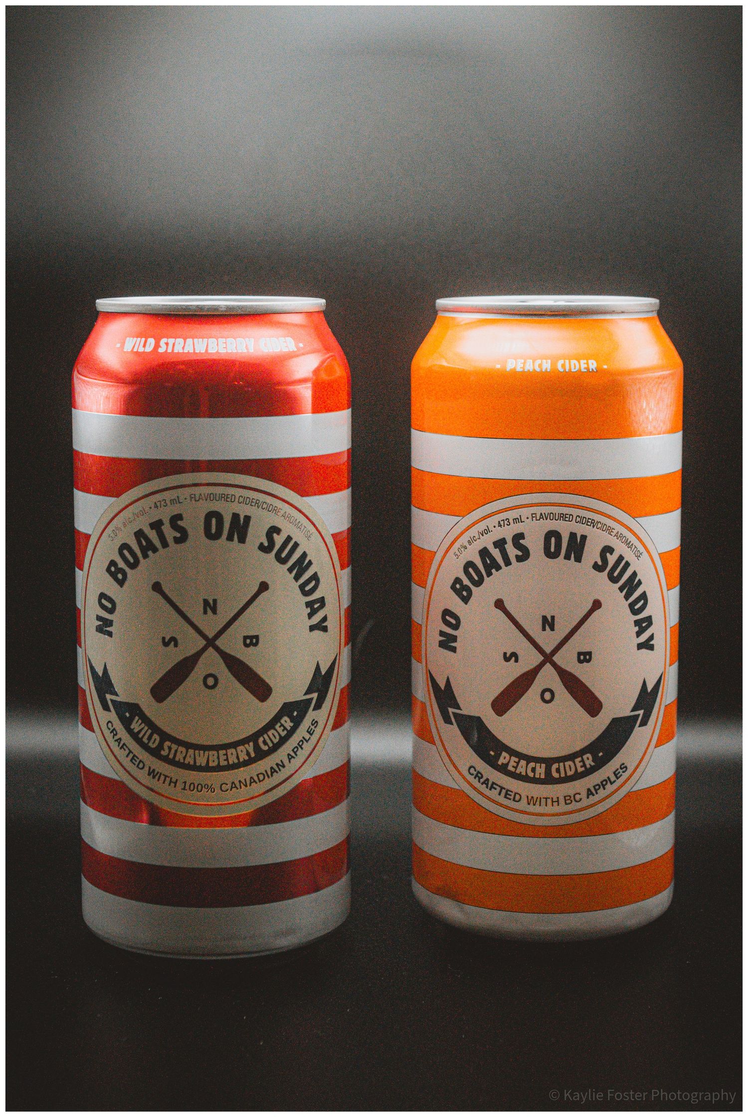 Two No Boats on Sunday cider cans, Wild Strawberry and Peach flavors, crafted with BC apples, displayed side by side.