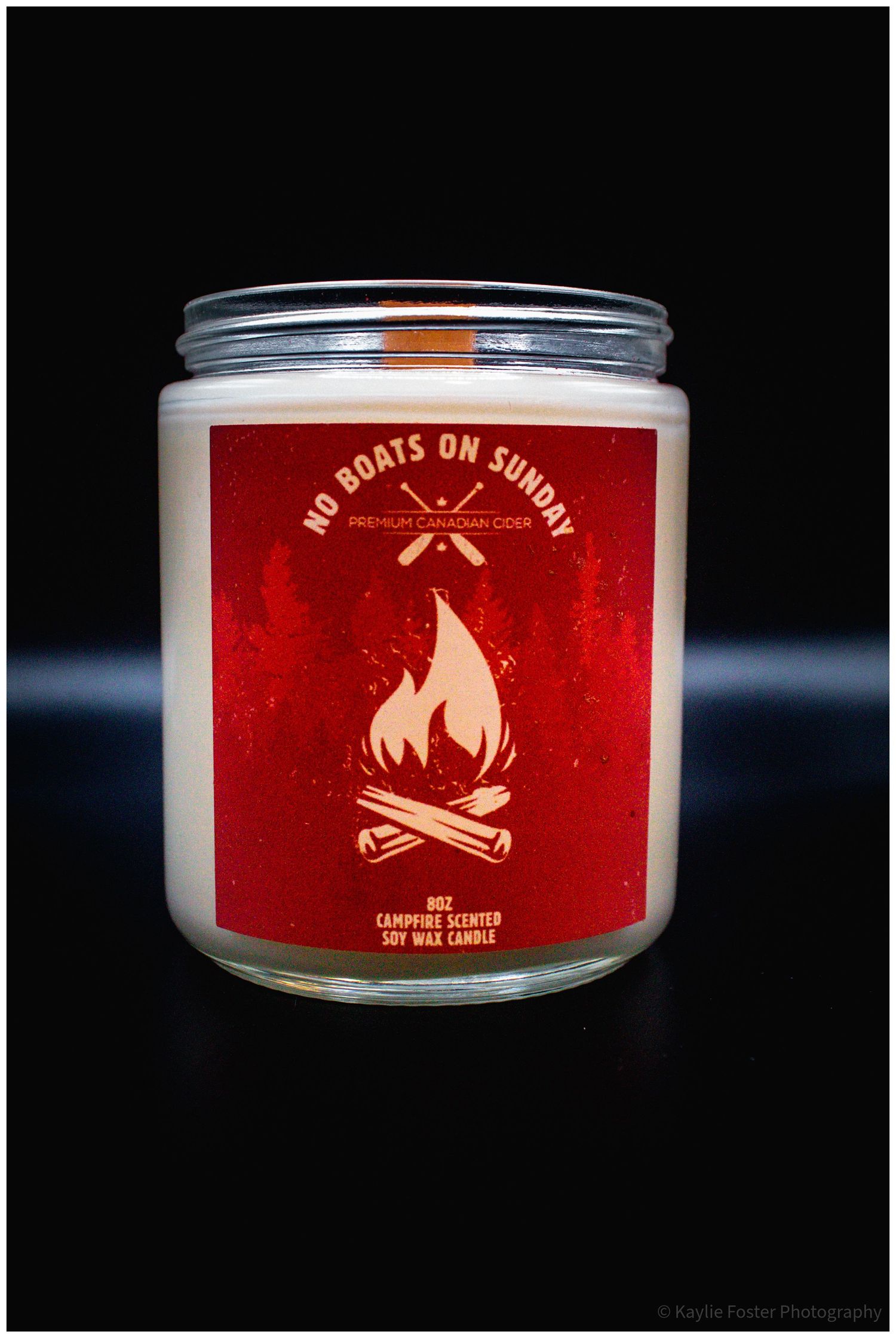 No Boats on Sunday campfire scented soy wax candle in a glass jar with a red label featuring a bonfire graphic.