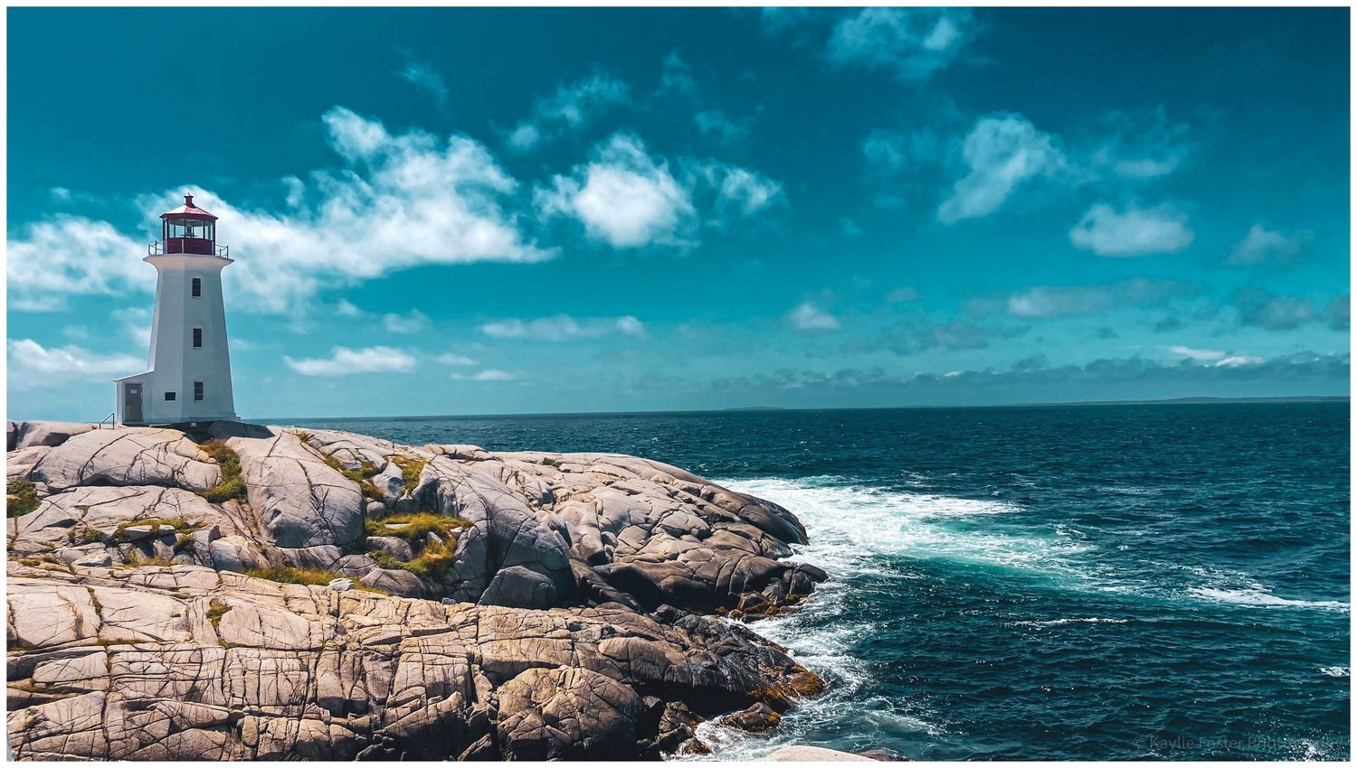 White lighthouse on rocky Atlantic coast with turquoise waves and dramatic cloudy sky.